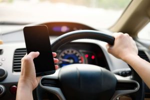 person-holding-black-smartphone-and-steering-wheel