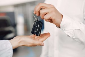 rental car agent passing the keys to a rental car to a person who needs a rental car after a car accident