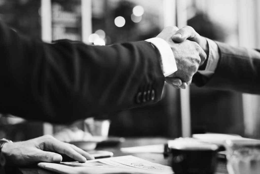 black and white photo of two attorneys shaking hands after finishing negotiations