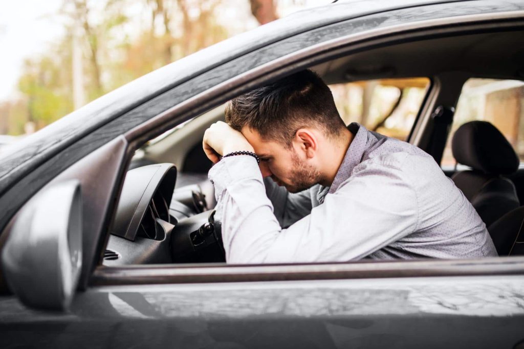 drowsy driver slumps over the steering wheel of his car