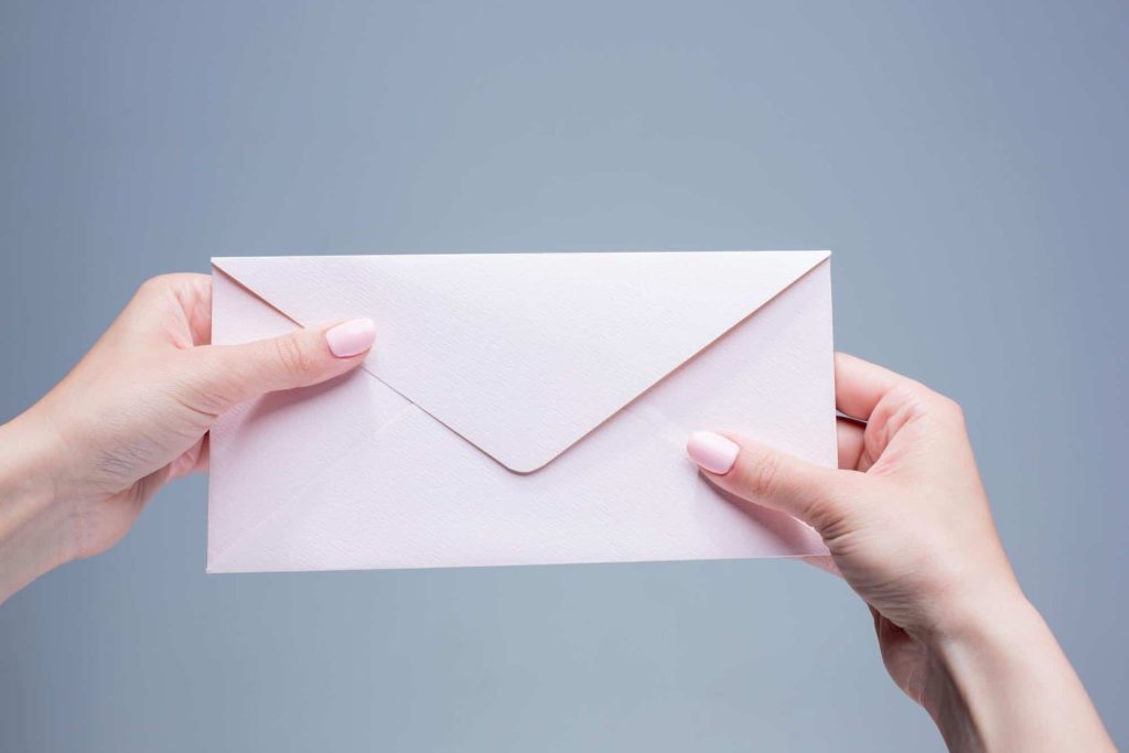 close up of hands holding an envelope to send through the mail