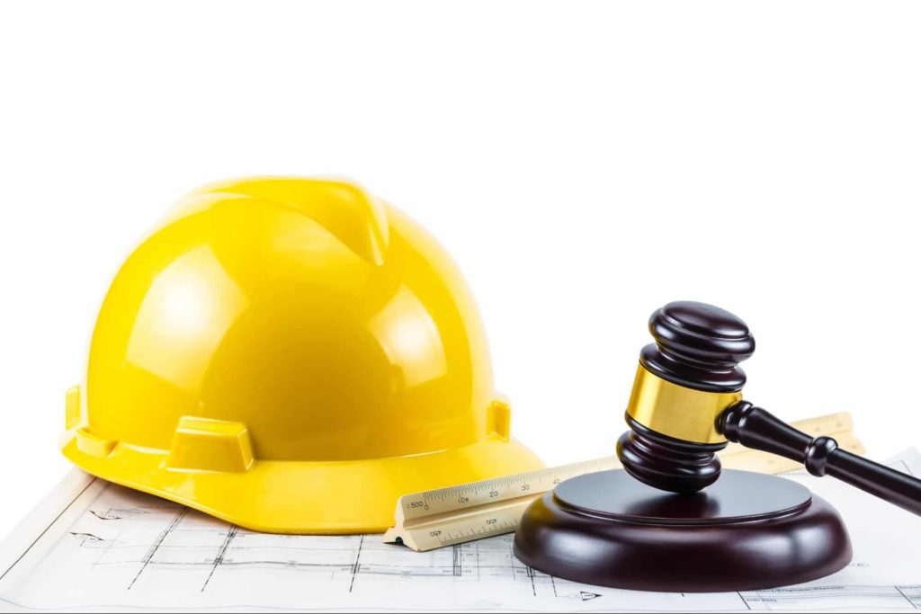 A construction worker's hard hat and a judge's gavel on a white background. Injured workers can receive help on their worker compensation claim from an attorney.