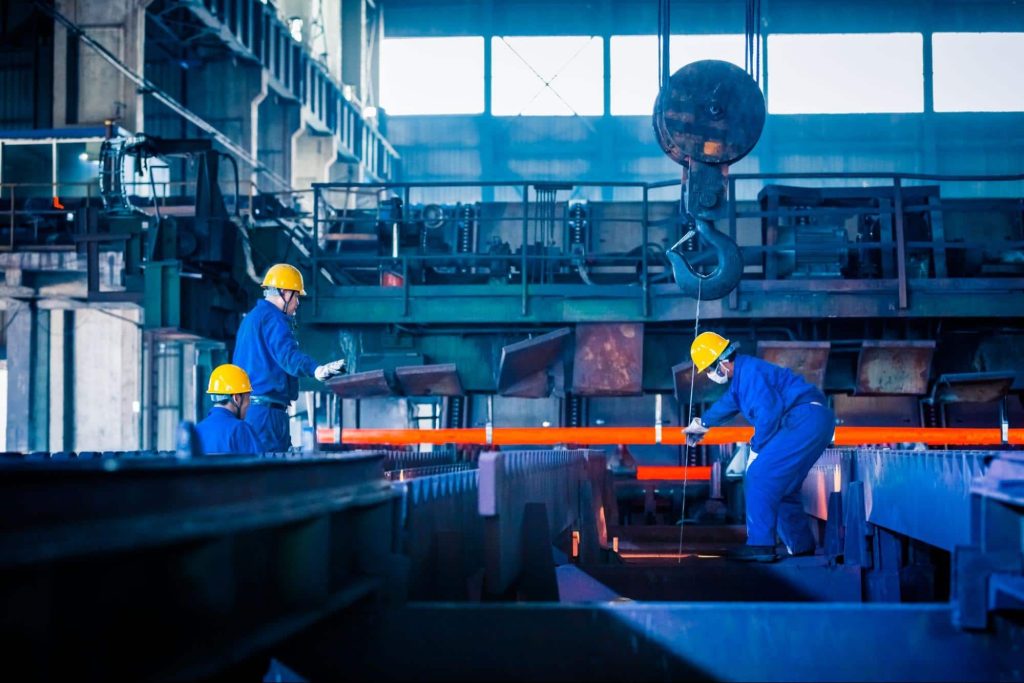 Three steel mill workers operating heavy machinery. Employees who are injured at work in dangerous jobs like this would receive a workers' compensation settlement.