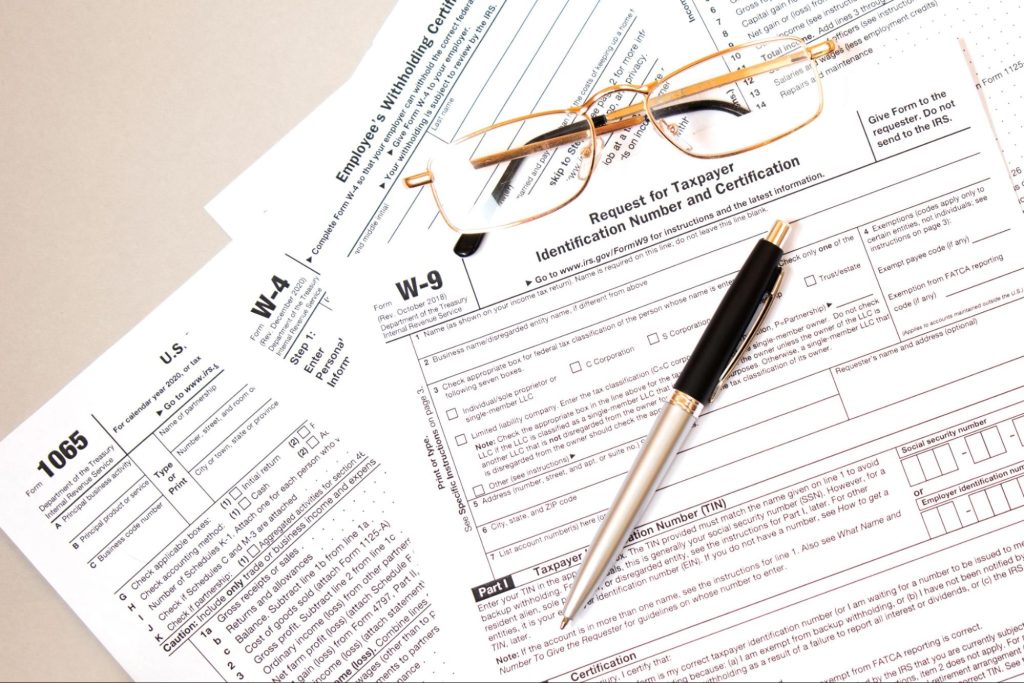 Federal tax forms on a table with glasses and a pen. Filing taxes can be confusing and if you have a workers compensation payments it may make you more confused about how to file.