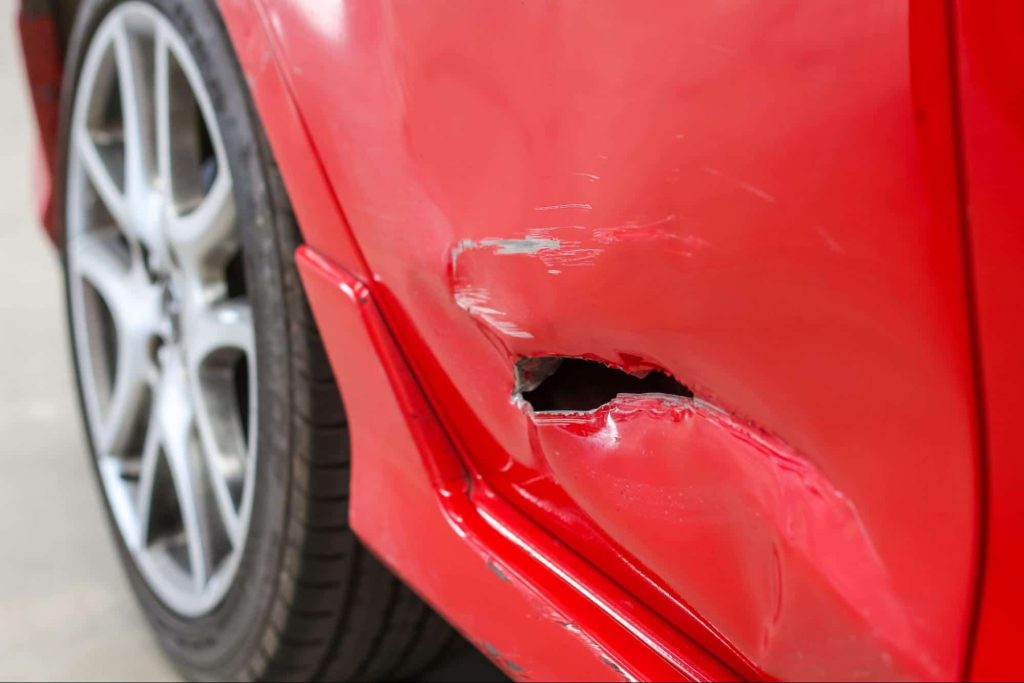 car rear quarter panel with hole from accident Close up of a car with a hole in the passenger door after an accident. This sort of damage will reduce the value of the car and a diminished value claim will help the owner recover for the loss in value.