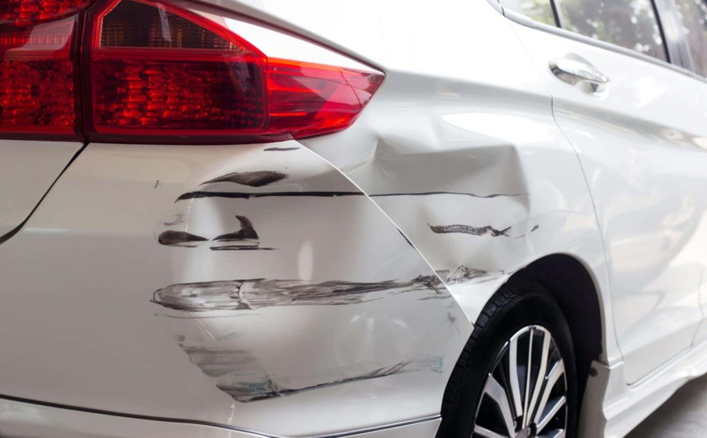 car with damaged rear bumper Close up of a car with a dented and scratched rear bumper. This type of damage will lead to the value of the car decreasing.