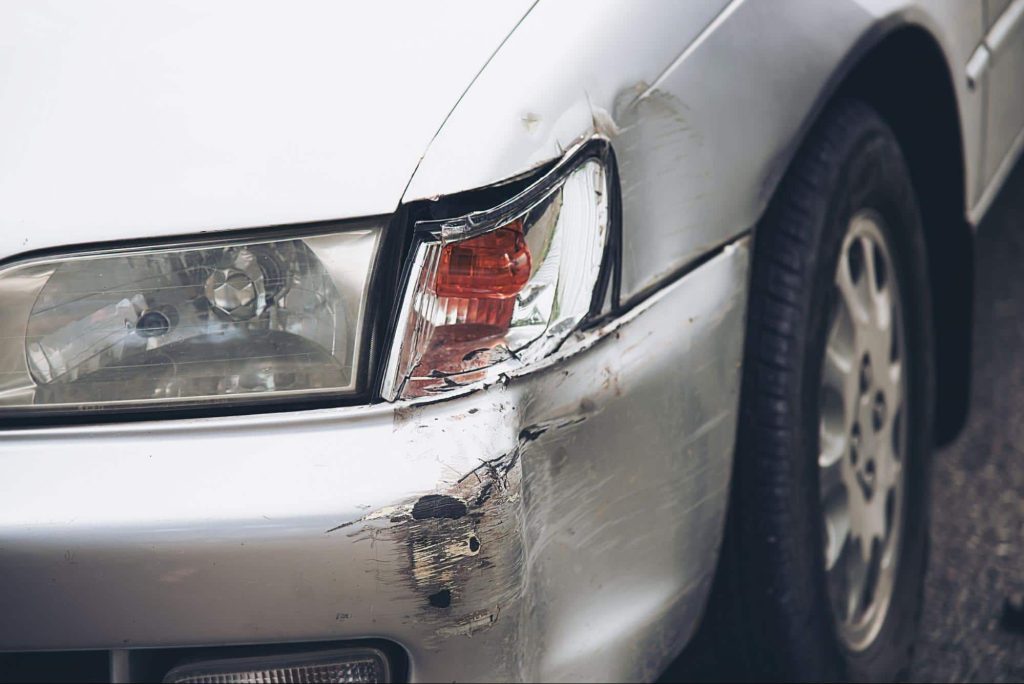 Close up of a car with a damaged front bumper and headlight after an accident that resulted in minor property damage.