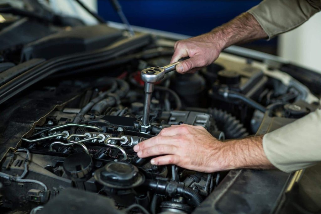 mechanic fixing damaged engine A mechanic works on the engine of a car that was damaged in an accident.