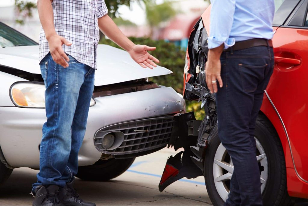 An insured driver and an uninsured driver exchange information at the scene of a rear end car accident.