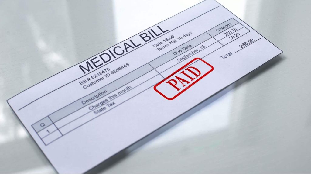 A paid medical bill sitting atop a glossy white table top.