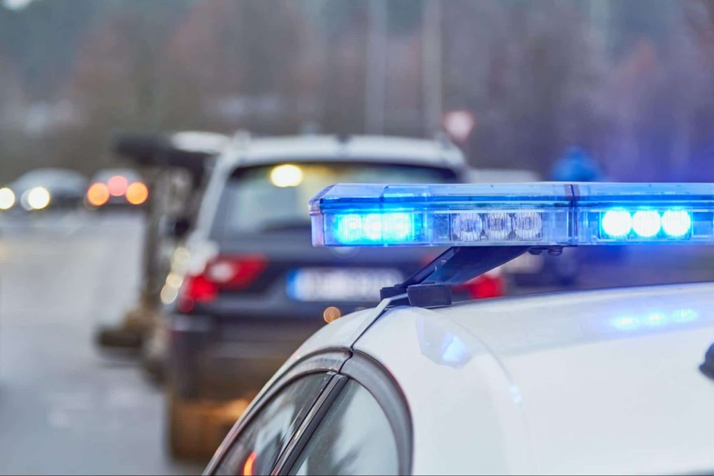 A police car at the scene of a serious car accident where one of the vehicles has been flipped on its side.