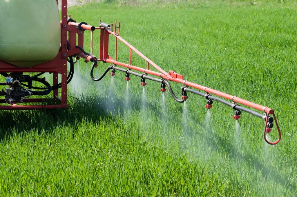 Tractor spraying Paraquat in a field.