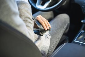 Woman putting seatbelt on in car.