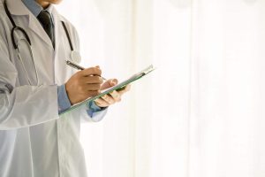 Doctor in lab coat holding clipboard and pen.