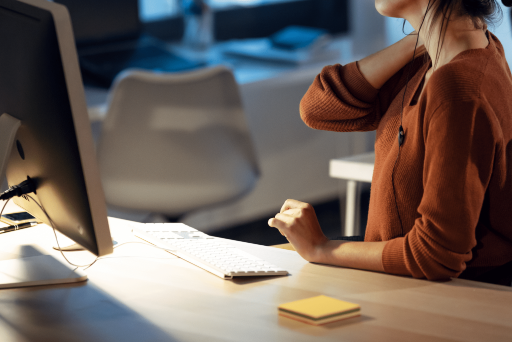 Woman at desk rubbing neck in pain